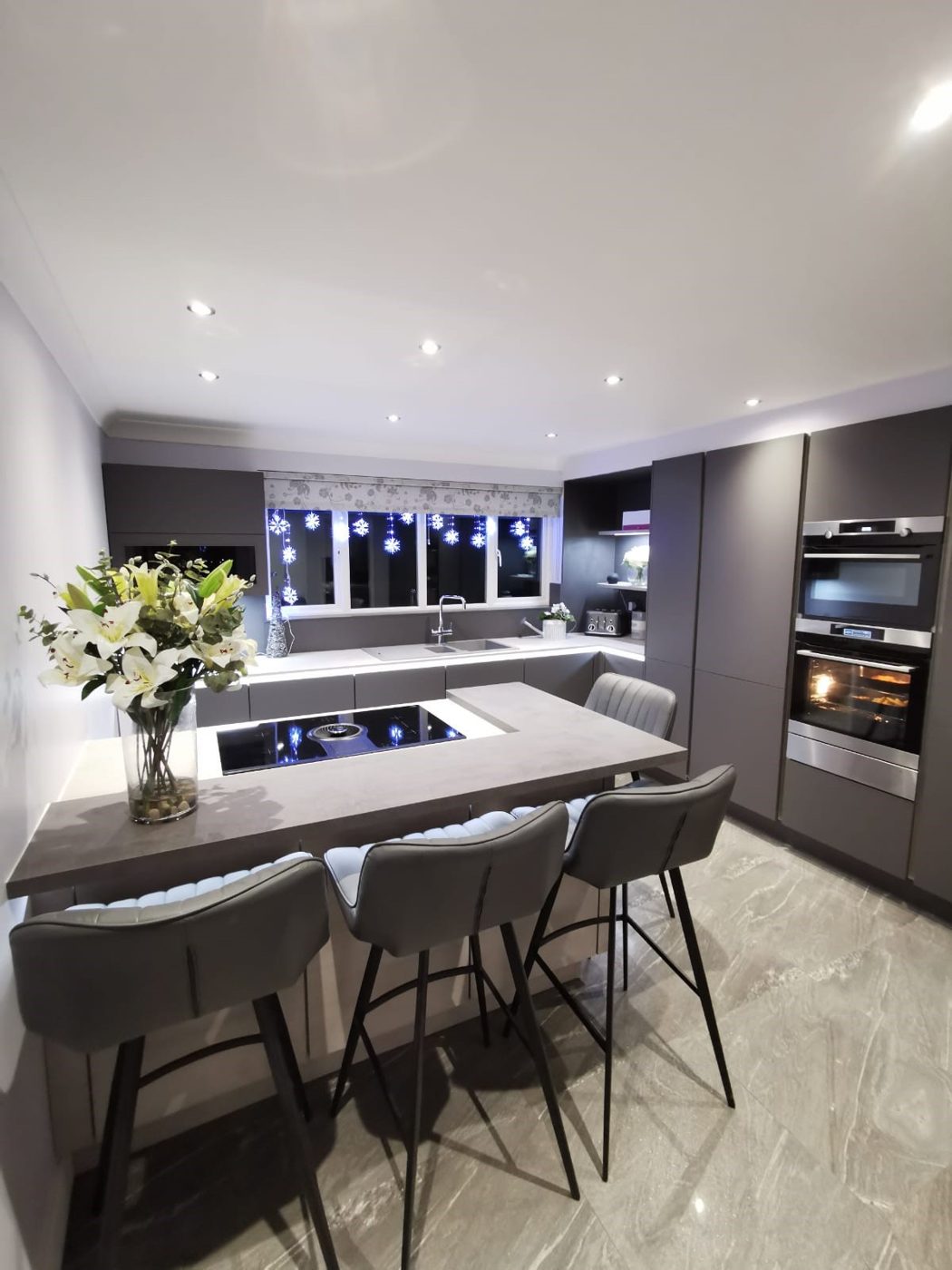 Grey handleless kitchen with peninsula breakfast bar and built-in ovens